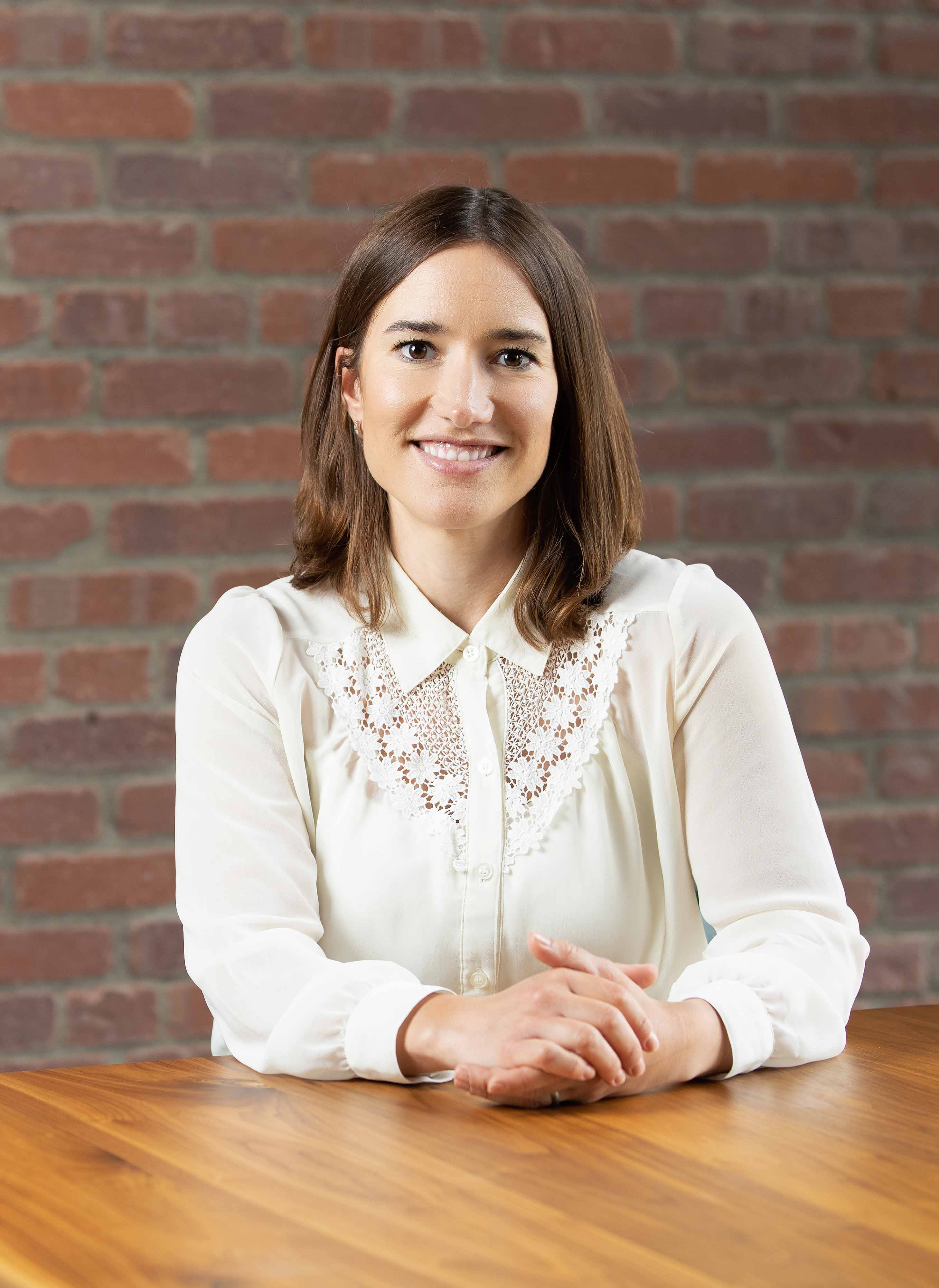 Elisabet smiling at her desk hands together