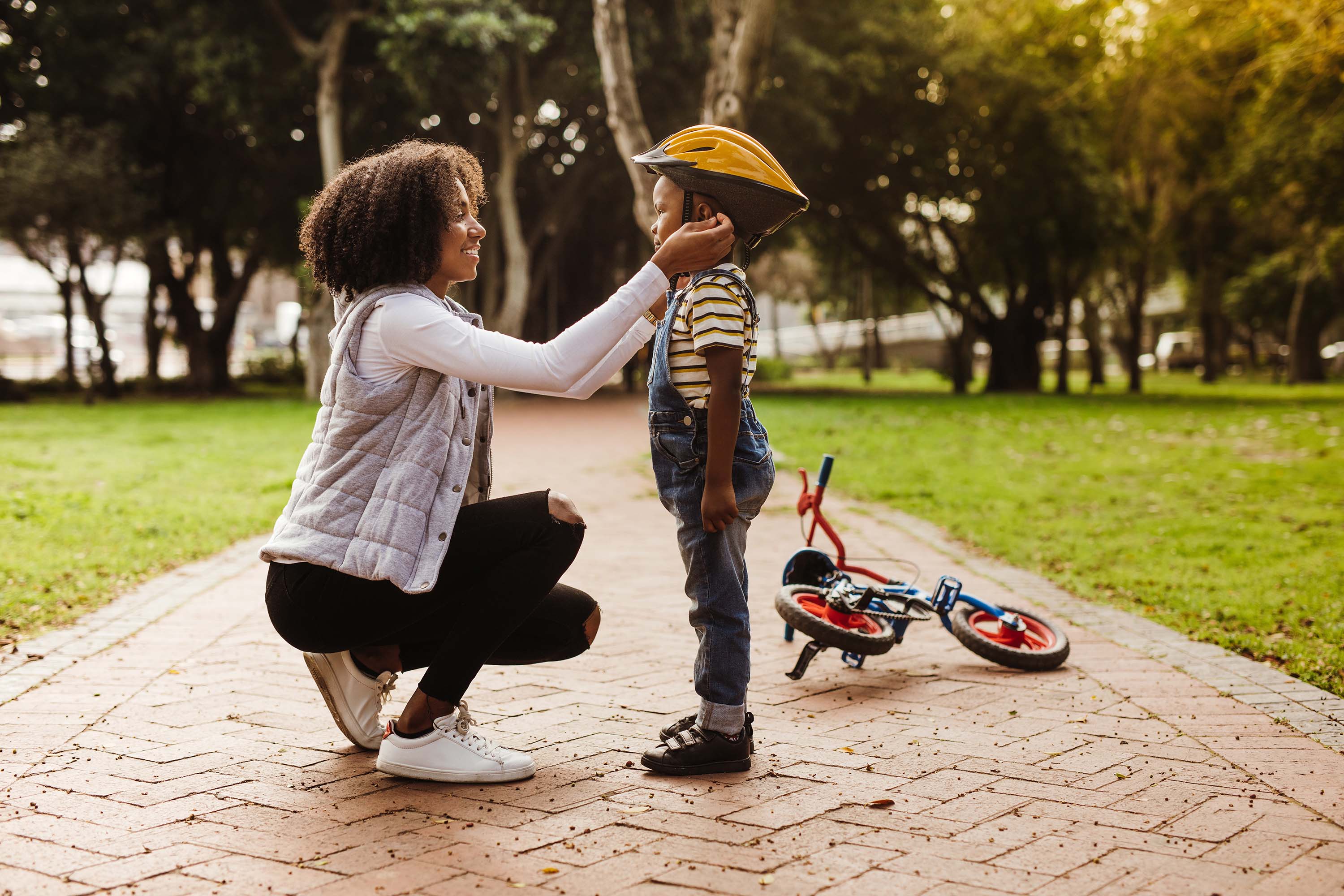 A mother helping kid wearing helmet