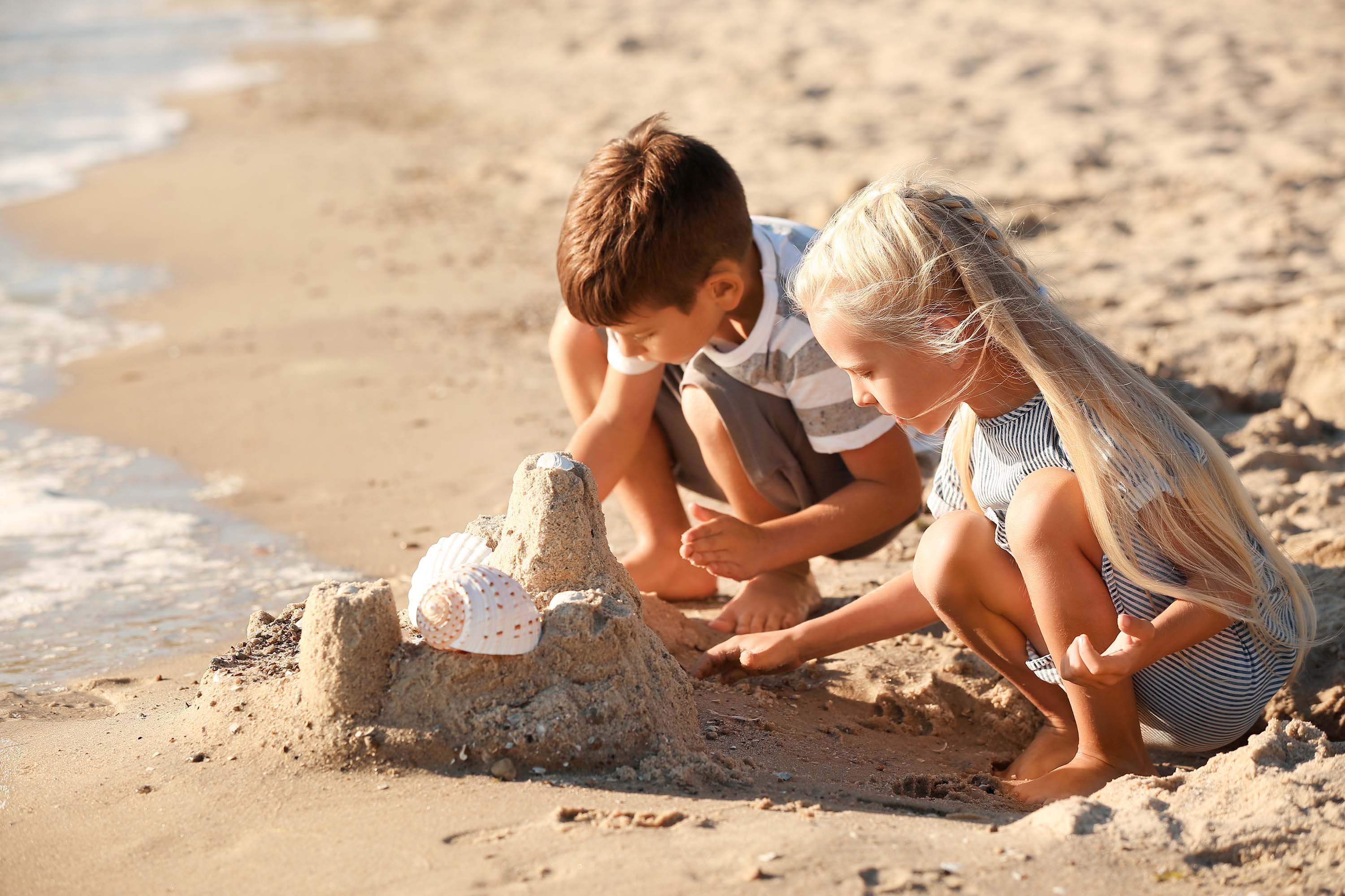 two kids playing with sand at beach
